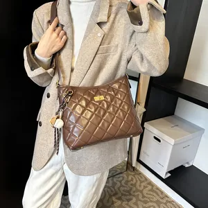 Sac bandoulière marron matelassé avec boucle dorée et chaîne porté sur l'épaule du mannequin