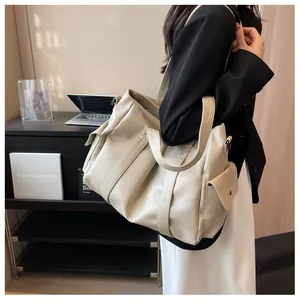 Détail d'un grand sac fourre-tout crème avec poche latérale et double bandoulière