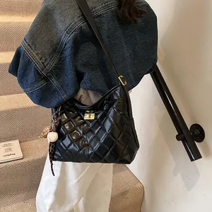 Sac bandoulière noir matelassé avec fermoir doré et accessoire de baseball