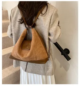 Detail of suede textured oversized tote with embossed logo and metallic ring hardware