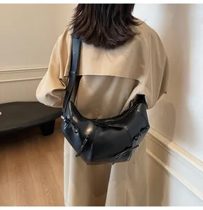 Détail du sac demi-lune noir avec nœuds porté sur un trench-coat de couleur kaki