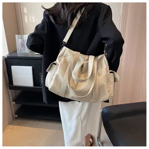 Détail du sac fourre-tout crème avec poches latérales et bandoulière porté par un mannequin