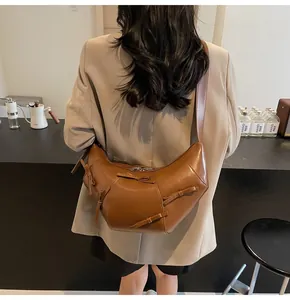 Détail d'un sac demi-lune marron orné de nœuds élégants et d'une large bandoulière en cuir