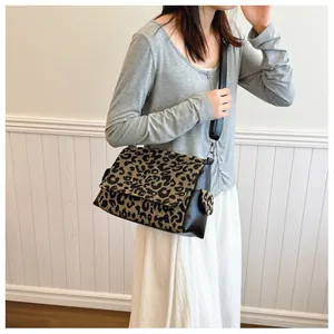 Detail of leopard print tote bag with black strap worn by a model in a casual setting