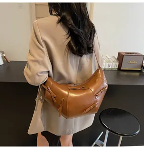Sac croissant marron à nœuds porté par un mannequin sur un blazer de couleur beige