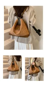 Detailed view of brown suede shoulder bag with leather trim and gold chain strap