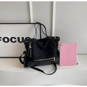 Détail d'un sac cabas noir avec fermeture éclair dorée et base en cuir