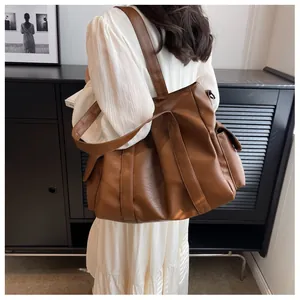 Gros plan du sac fourre-tout en similicuir caramel avec poche latérale et texture fine