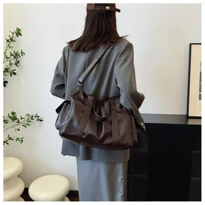 Deep brown tote bag detail with soft pleated texture and adjustable crossbody strap