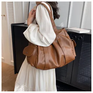 Gros plan d'un grand sac cabas marron avec poches latérales sur robe crème