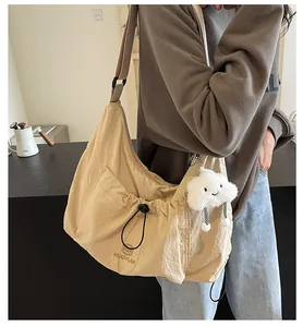 Detail view of khaki large crossbody bag with adjustable drawstring pocket and plush charm
