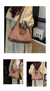 Detail of a brown suede hobo bag with embossed bear logo and adjustable chain strap