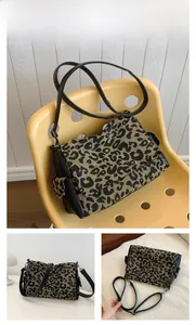 Close-up of leopard print fabric and black matte leather panels on a crossbody tote bag