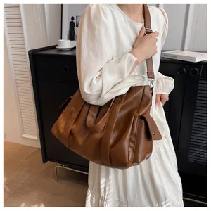 Détail du sac cabas en cuir marron avec large bandoulière porté par un mannequin
