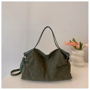 Detail view of dark green suede tote bag with contrast handles and fine stitching