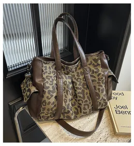 Close-up of leopard print canvas tote bag with brown leather side pockets and handles
