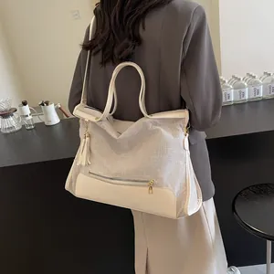 Grand sac cabas tissé avec patchwork de cuir et pompon présenté dans un café chic