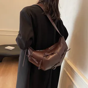 Sac bandoulière demi-lune marron avec nœud porté par un mannequin pour un look d'automne