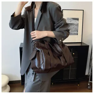 Detail view of large dark brown tote bag with side pocket and adjustable shoulder strap