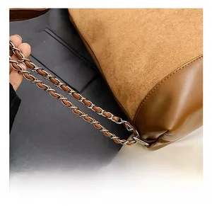 Close-up of brown suede and leather stitching with metal chain strap details
