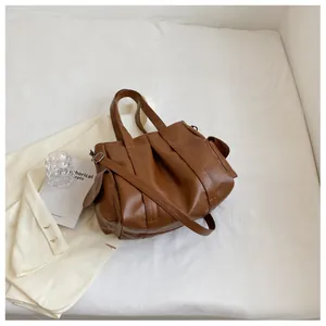 Détail d'un grand sac cabas marron en similicuir avec plusieurs poches et boucles métalliques