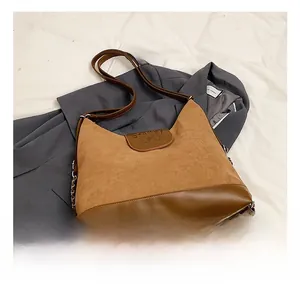 Detail showing two-tone suede and leather tote bag with long strap on grey blazer