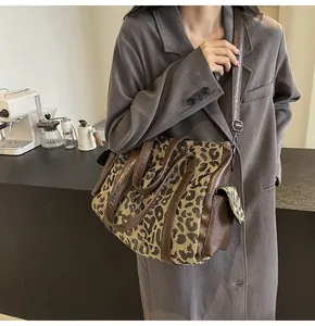 Detailed view of leopard print tote bag with brown leather straps in a cafe setting