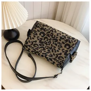 Close-up of leopard print jacquard fabric and black leather strap on a vintage tote bag