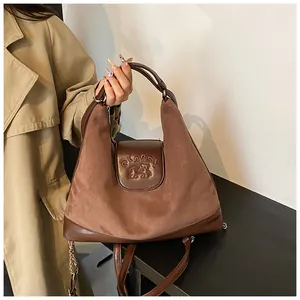 Close-up of brown suede tote bag with embossed bear pattern and metal chain strap