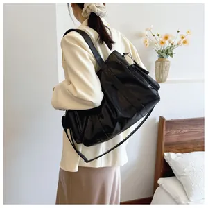Close-up of a black large capacity tote bag with adjustable shoulder straps in a cozy room