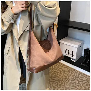 Detail of a large brown suede tote bag with bear embossing and premium metal chain