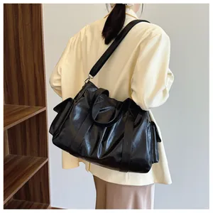 Macro detail of black large tote bag with glossy leather texture and side flap pockets