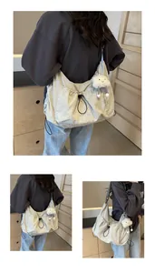 Detail of grey lightweight nylon messenger bag with drawstring design and plush cloud charm