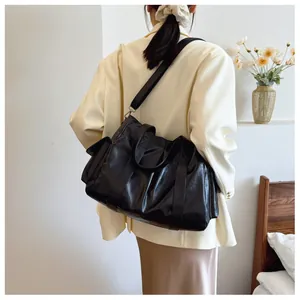 Large black PU leather tote bag shown on model in an elegant lifestyle home setting