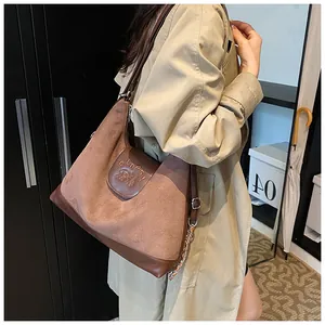 Detail of a large brown suede tote bag with leather flap and stylish silver chain strap