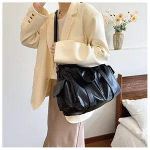 Detailed view of black faux leather tote bag with flap side pockets and adjustable strap