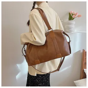 Rückansicht einer Frau mit einer großen braunen PU-Leder-Tote-Bag mit Kreuzstichdetails