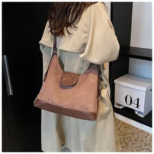 Detail of a brown textured dual-material crossbody bag with gold chain strap