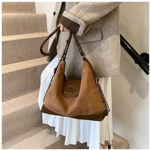 Detail of vintage brown tote with embossed flap, chain decor and adjustable strap
