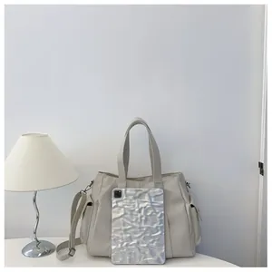 Detail of cream tote bag featuring side flap pockets and adjustable crossbody strap