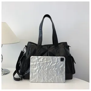 Detail der großen schwarzen Shopper-Tasche aus glänzendem PU-Leder mit praktischer Seitentasche