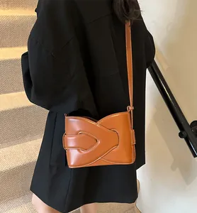 Detail view of brown crossbody bag featuring distinctive crisscross design and white stitching