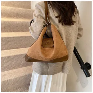 Detail of vintage brown suede crossbody bag with contrast leather trim and logo