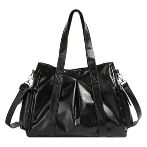 Classic black high-gloss tote bag with double handles and adjustable crossbody strap