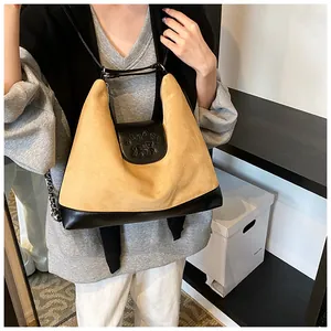 Detail of matte suede texture and bear embossed flap on large commuter shoulder bag