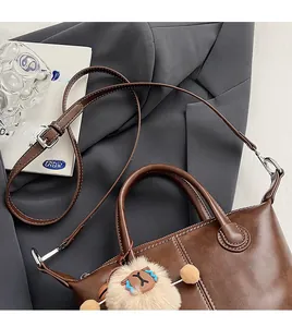 Detail of brown leather tote bag with white contrast stitching and plush sheep charm