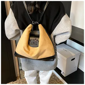 Detail of khaki suede and black leather patchwork backpack worn by a model in a casual setting