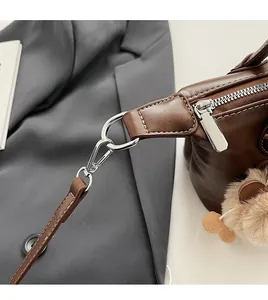 Close-up of brown PU leather tote with silver buckle and plush bear charm detail