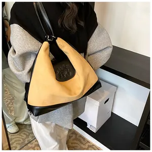 Detail of suede tote bag showing embossed CLAPS dog logo and black leather strap