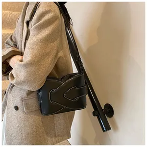 Detail of black crescent shoulder bag featuring contrast white stitching and knot design